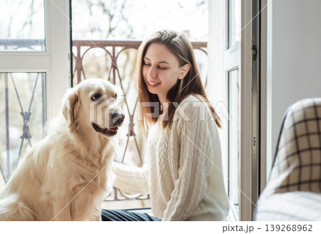 Woman and golden retriever dog sharing happy moment indoors Woman and golden retriever dog sharing happy moment indoors 139268962