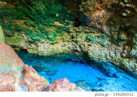 View of beautiful natural pool of crystal clear water formed in a rocky cave with stalagmites and stalagmites. Kuza cave in Zanzibar, Tanzania 139269312