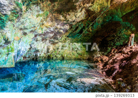 View of beautiful natural pool of crystal clear water formed in a rocky cave with stalagmites and stalagmites. Kuza cave in Zanzibar, Tanzania 139269313