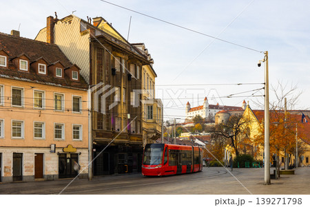 Modern tram travels along a quiet Hurbanovo street in Bratislava during day with historical architecture in view Modern tram travels along a quiet Hurbanovo street in Bratislava during day with historical architecture in view 139271798
