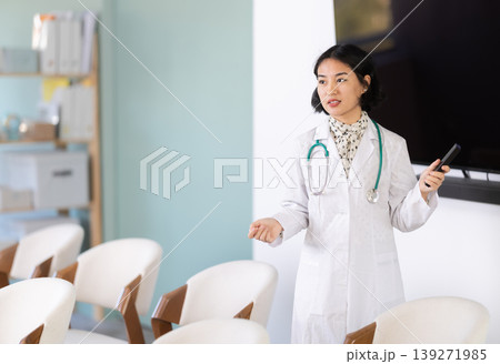 Female doctor gives lecture in classroom while holding remote control 139271985