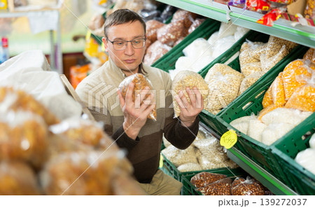 Man examining packages with dried almond, choosing nuts in grocery store Man examining packages with dried almond, choosing nuts in grocery store 139272037