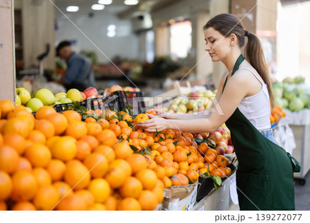 Woman seller laying oranges on counter Woman seller laying oranges on counter 139272077
