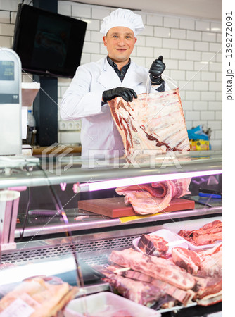 Adult man puts beef ribs in showcase Adult man puts beef ribs in showcase 139272091