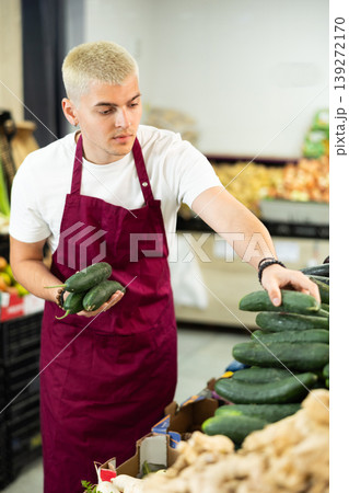 Guy shop seller puts cucumber goods on display case Guy shop seller puts cucumber goods on display case 139272170