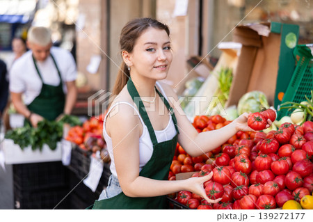 Female seller laying out tomatoes on the counter Female seller laying out tomatoes on the counter 139272177