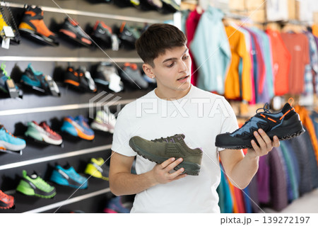 Guy in sports store chooses shoes for autumn hiking 139272197