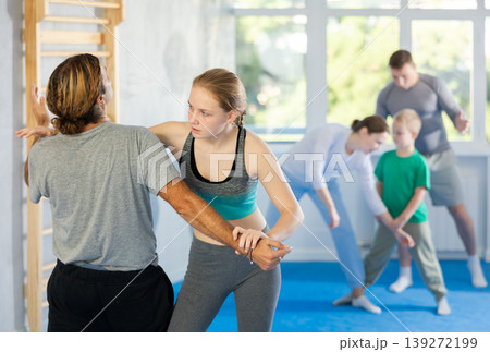 Teen girl in self-defense training in gym practices trip up her opponent during sparring Teen girl in self-defense training in gym practices trip up her opponent during sparring 139272199