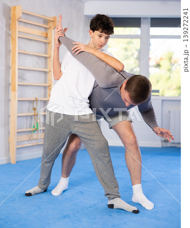 Father teaching his son wrestling or self-defense techniques in gym Father teaching his son wrestling or self-defense techniques in gym 139272241