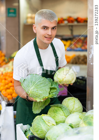 Guy shop seller puts cabbage goods on display case 139272283