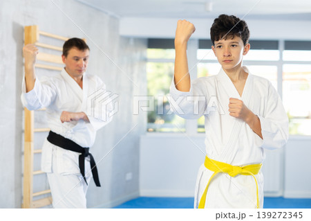 Karate trainer teaching block and punches to teenager in the gym 139272345