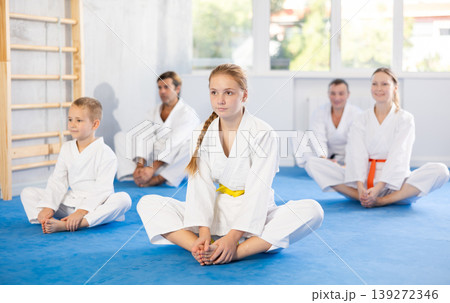 Big family before training karate martial arts performs stretching butterfly Big family before training karate martial arts performs stretching butterfly 139272346