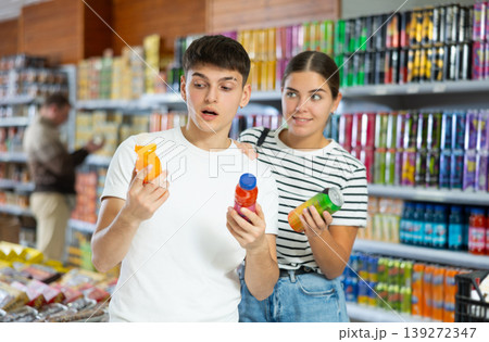 Young married couple chooses drink bottle in store to buy them Young married couple chooses drink bottle in store to buy them 139272347