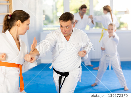 Woman is paired with man teacher to learn how to strike and rehearses blocking opponent Woman is paired with man teacher to learn how to strike and rehearses blocking opponent 139272370