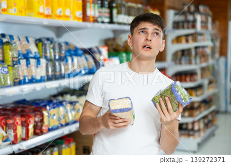 Guy carefully checks the information on product labels in hypermarket 139272371
