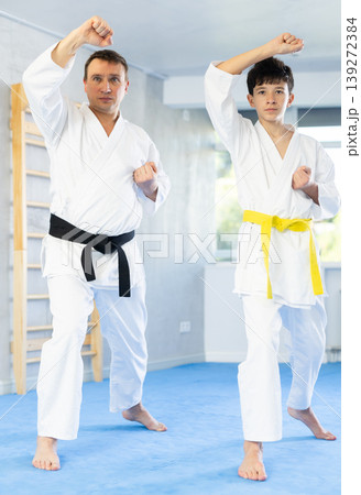Individual karate lesson for teenager - fighting position of teenager and coach during karate training in gym Individual karate lesson for teenager - fighting position of teenager and coach during karate training in gym 139272384