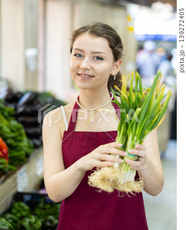 Young saleswoman offering green onions 139272405