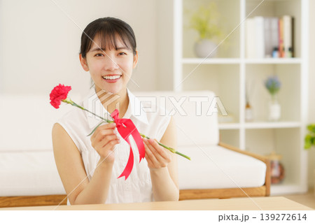 母の日 自宅のリビングでカーネーションを渡す若い日本人の女の子 母の日 自宅のリビングでカーネーションを渡す若い日本人の女の子 139272614