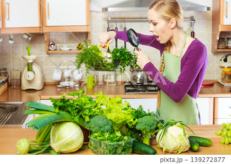 Woman looking through magnifier at vegetables basket Woman looking through magnifier at vegetables basket 139272877