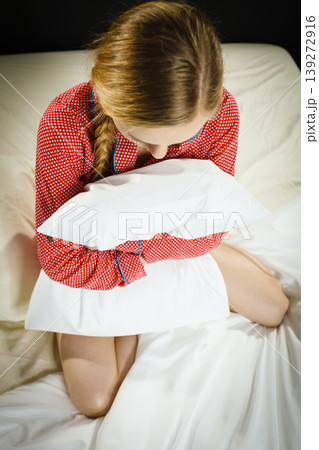 Sad depressed girl in bed gripping pillow Sad depressed girl in bed gripping pillow 139272916