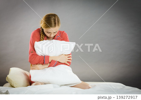 Sad depressed girl in bed gripping pillow Sad depressed girl in bed gripping pillow 139272917