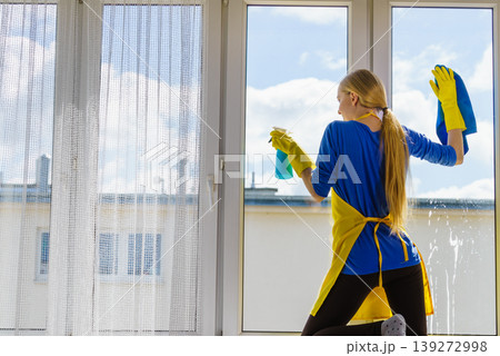 Woman cleaning window at home Woman cleaning window at home 139272998