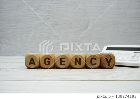 AGENCY alphabet letters with calculator on wooden background AGENCY alphabet letters with calculator on wooden background 139274195