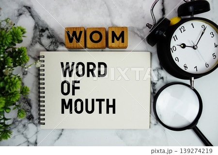 WOM Word of Mouth text with alarm clock and magnifying glass on marble background WOM Word of Mouth text with alarm clock and magnifying glass on marble background 139274219