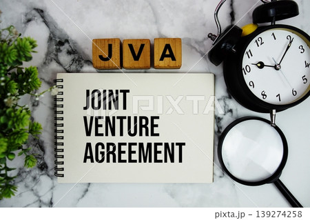 JVA Joint Venture Agreement text with alarm clock and magnifying glass on marble background JVA Joint Venture Agreement text with alarm clock and magnifying glass on marble background 139274258