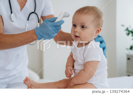Temperature of body measurement. Female doctor is taking care of little baby girl in the clinic 139274364