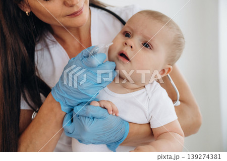 In the clinic. Female doctor is taking care of little baby girl In the clinic. Female doctor is taking care of little baby girl 139274381