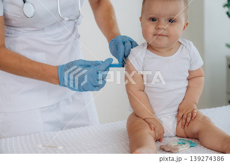 Injection time process. Female doctor is taking care of little baby girl in the clinic Injection time process. Female doctor is taking care of little baby girl in the clinic 139274386