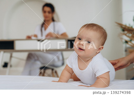 Resting on the white surface. Female doctor is taking care of little baby girl in the clinic Resting on the white surface. Female doctor is taking care of little baby girl in the clinic 139274398