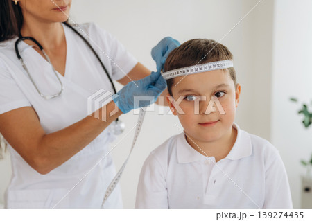 Measuring the width of head. Boy is in routine appointment in clinic with female doctor 139274435