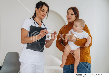 Medicine is in hands. Mother with her little baby daughter is in clinic with doctor at appointment 139274490