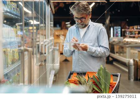 A senior man is buying food in the grocery store A senior man is buying food in the grocery store 139275011