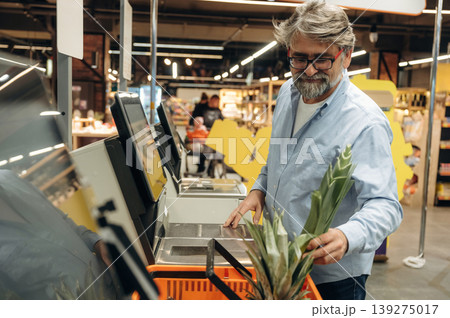 With big pineapple. A senior man is buying food in the grocery store With big pineapple. A senior man is buying food in the grocery store 139275017