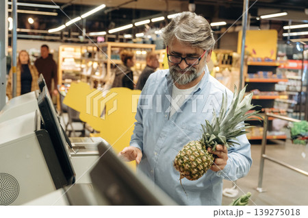With big pineapple. A senior man is buying food in the grocery store With big pineapple. A senior man is buying food in the grocery store 139275018