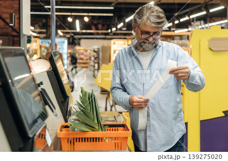Standing at the checkout. A senior man is buying food in the grocery store Standing at the checkout. A senior man is buying food in the grocery store 139275020