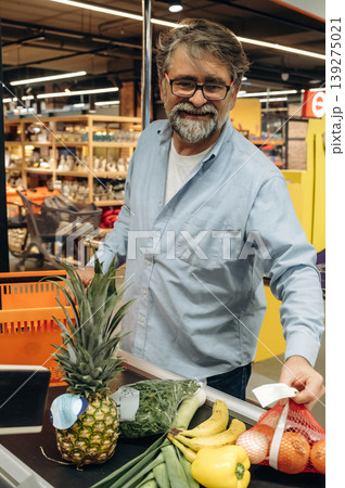 Standing at the checkout. A senior man is buying food in the grocery store 139275021