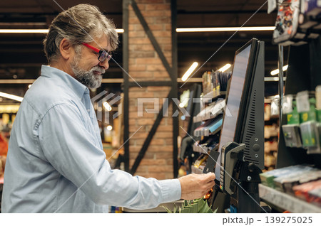 Paying by using credit card. A senior man is buying food in the grocery store 139275025
