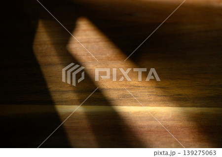 Play of light and shadow on a wooden surface creates a warm, textured ambiance 139275063