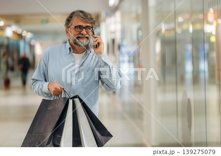 Making a call, talking. Senior man is in the mall, shopping time conception Making a call, talking. Senior man is in the mall, shopping time conception 139275079
