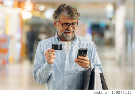 Wireless payment by using credit card and smartphone. Senior man is in the mall, shopping time conception 139275113