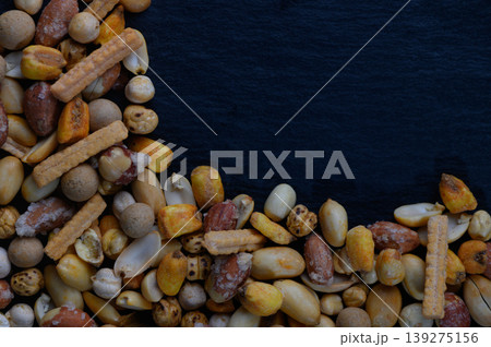 Colorful assortment of mixed nuts and snacks arranged artistically on a dark background, showcasing their textures and shapes Colorful assortment of mixed nuts and snacks arranged artistically on a dark background, showcasing their textures and shapes 139275156