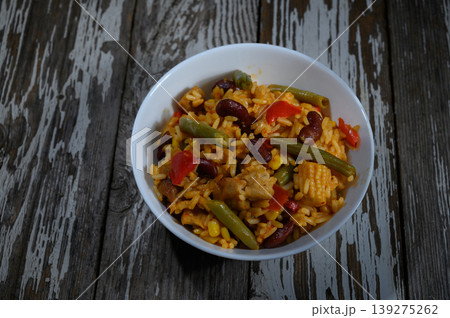 Colorful rice dish brimming with vegetables and beans evokes a sense of comfort and warmth on a rustic wooden table Colorful rice dish brimming with vegetables and beans evokes a sense of comfort and warmth on a rustic wooden table 139275262