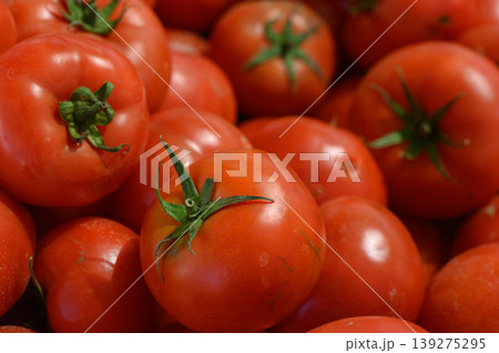 Fresh red tomatoes piled high in a vibrant market stall, inviting shoppers to indulge in nature's bounty of flavors Fresh red tomatoes piled high in a vibrant market stall, inviting shoppers to indulge in nature's bounty of flavors 139275295