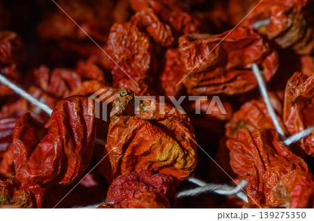Dried red chili peppers hanging in a traditional marketplace showcasing vibrant colors and rich textures Dried red chili peppers hanging in a traditional marketplace showcasing vibrant colors and rich textures 139275350