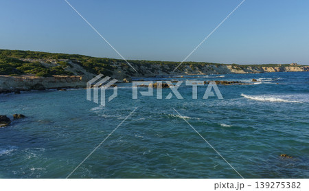 Serene coastal view at sunset with gentle waves lapping against rocky shoreline in summertime. Serene coastal view at sunset with gentle waves lapping against rocky shoreline in summertime. 139275382