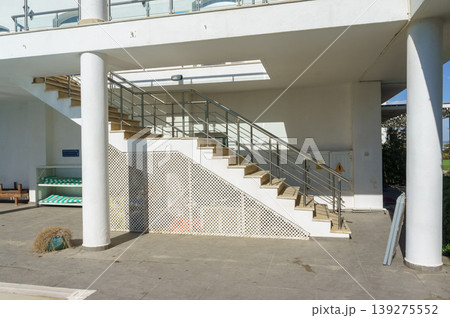 A modern staircase invites exploration in a sunlit contemporary space beside a tranquil pool. A modern staircase invites exploration in a sunlit contemporary space beside a tranquil pool. 139275552